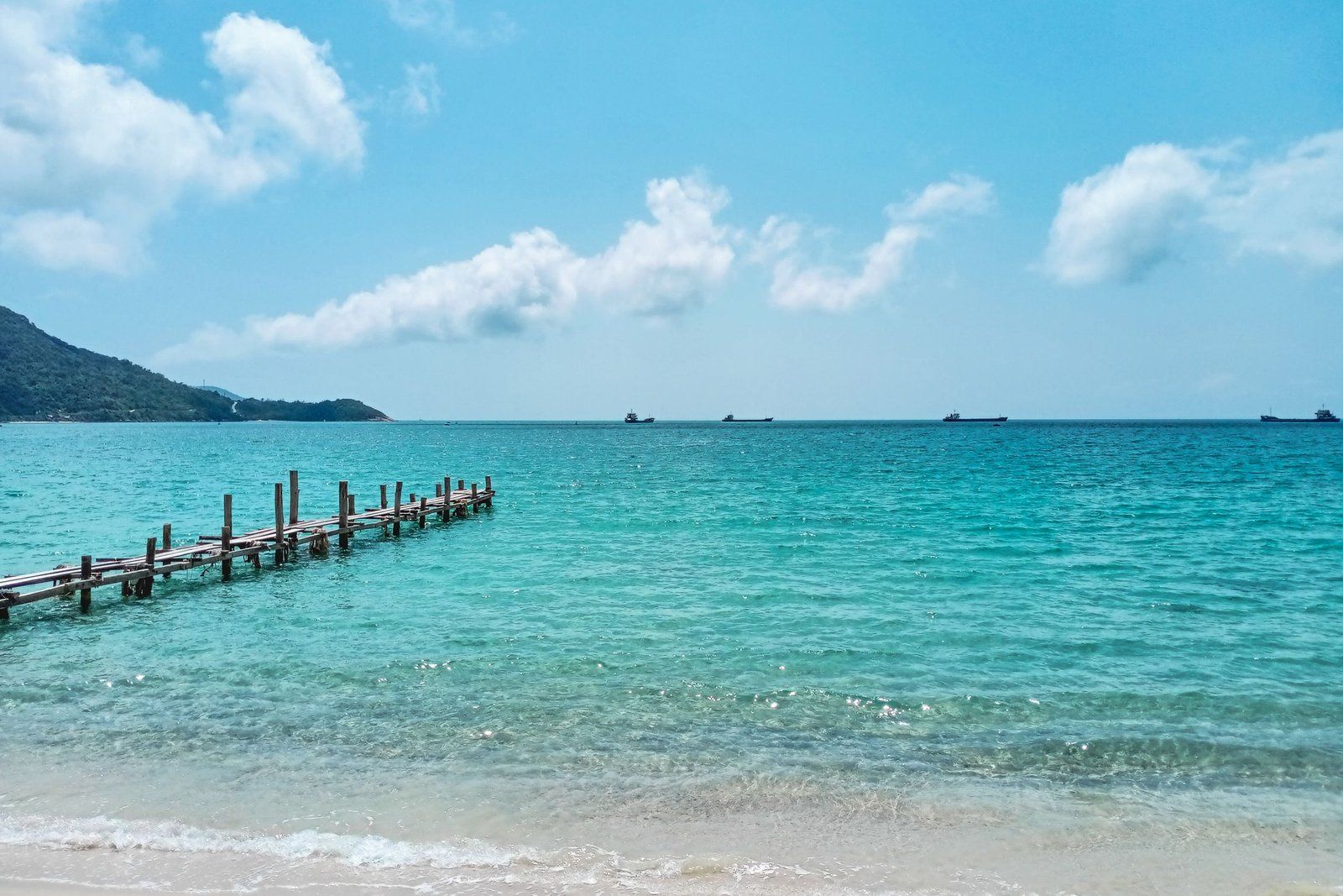 Деревянный пирс над бирюзовой водой на пляже недалеко от Хойана